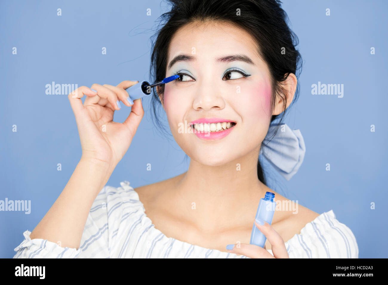Portrait of young smiling woman using makeup tool Stock Photo