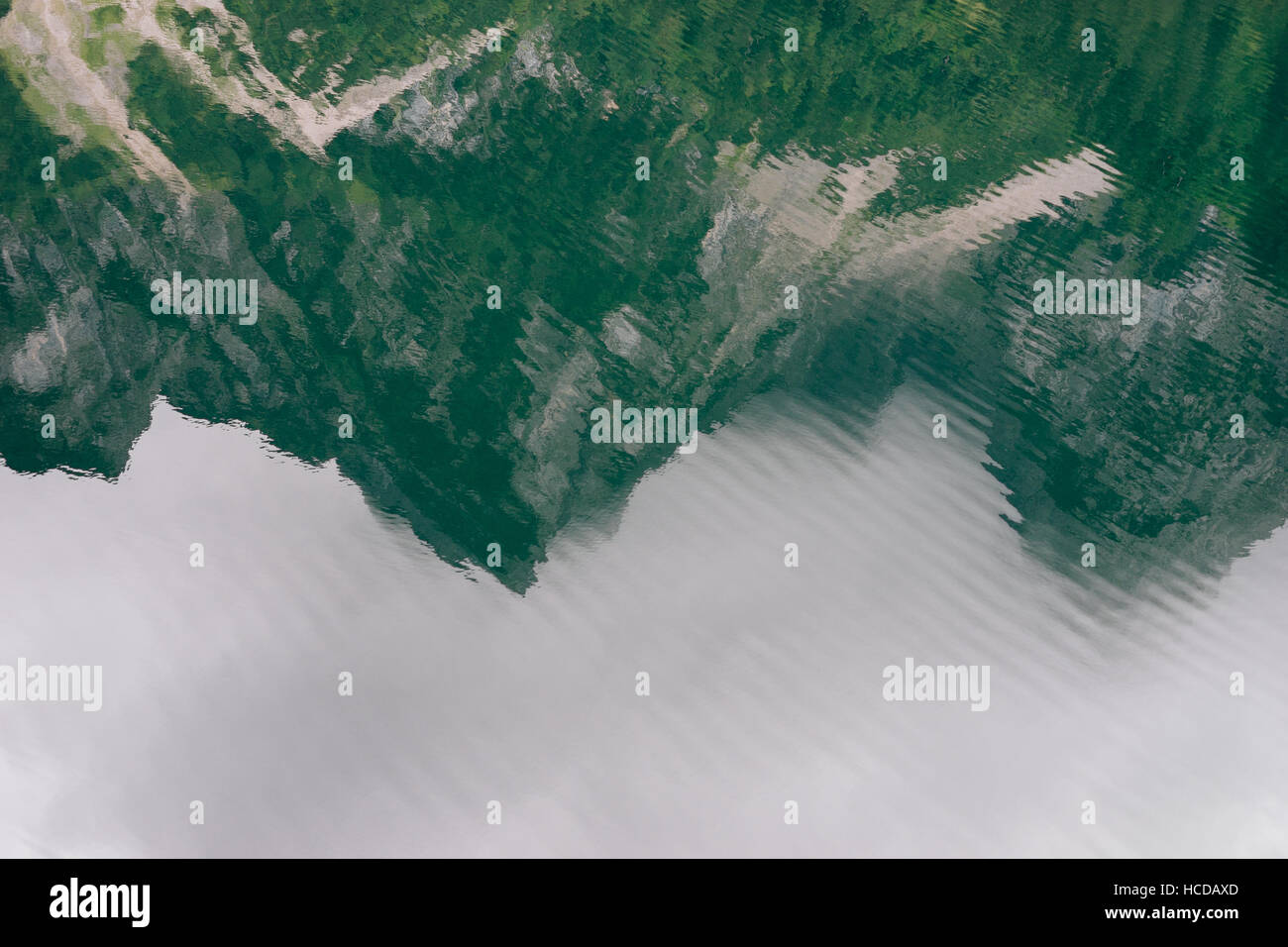 Rippled surface of lake and mountains reflection on water by cloudy day Stock Photo