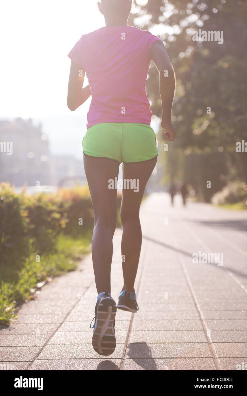Beautiful young sporty african american woman running at early morning