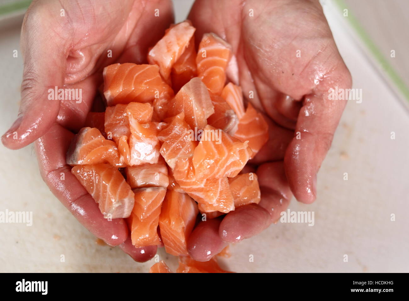 Hands with pieces of salmon fillet. Making Salmon in Puff Pastry Series. Stock Photo
