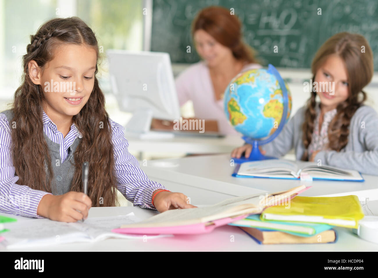 Teacher with two girls at lesson Stock Photo - Alamy