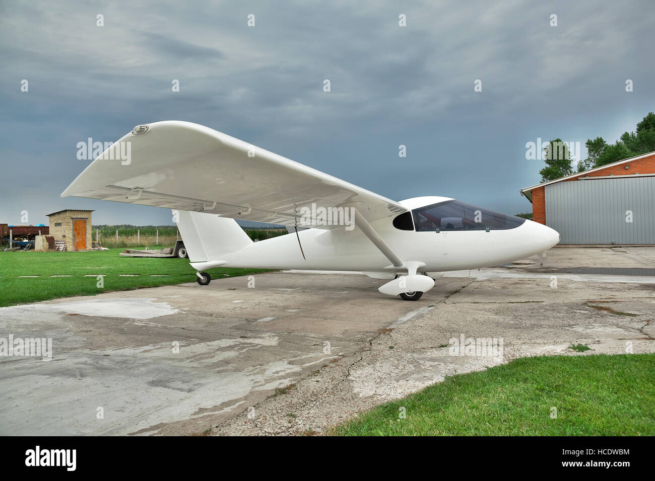 Kiev Region, Ukraine - July 19, 2014: Light private twin-engine plane parked on an airfield with stormy sky and hangar on the background Stock Photo