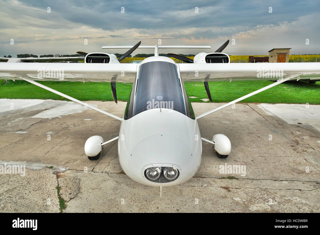 Kiev Region, Ukraine - July 19, 2014: Light private twin-engine plane parked on an airfield with stormy sky the background - front view Stock Photo