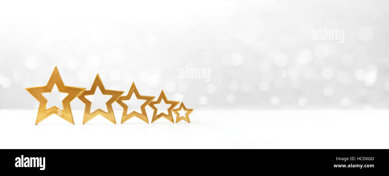 Five golden shining stars on white background with sparkling lights, symbol for winter and snow, copy space, banner format Stock Photo