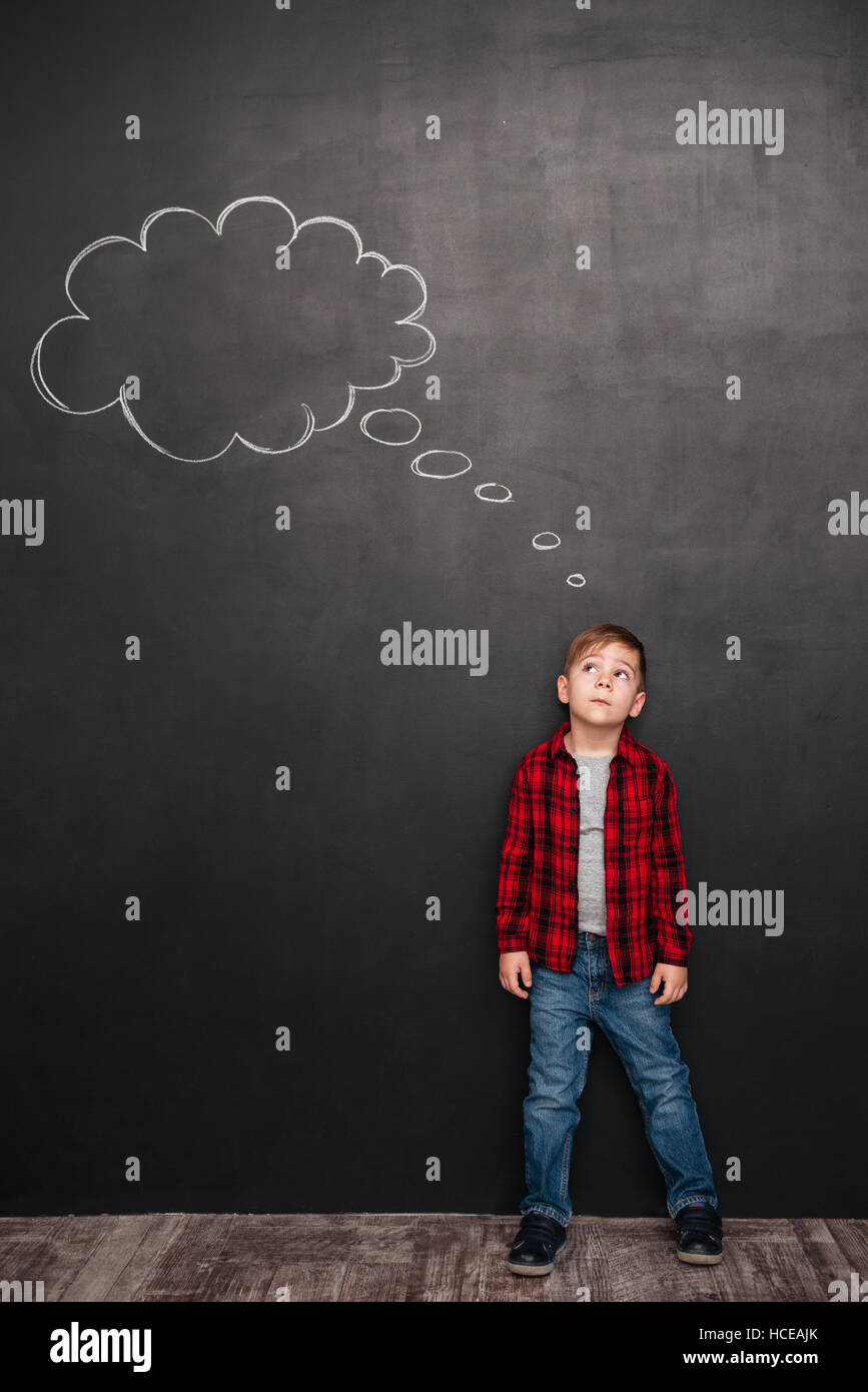 Child thinking with a thought bubble on the chalkboard concept for confusion, inspiration and solution Stock Photo