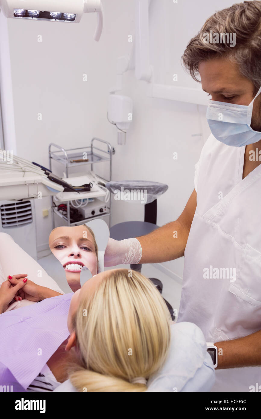 Dentist holding a mirror near patients face Stock Photo
