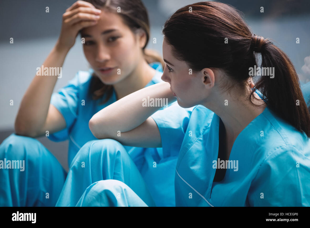 Sad nurses sitting on corridor Stock Photo