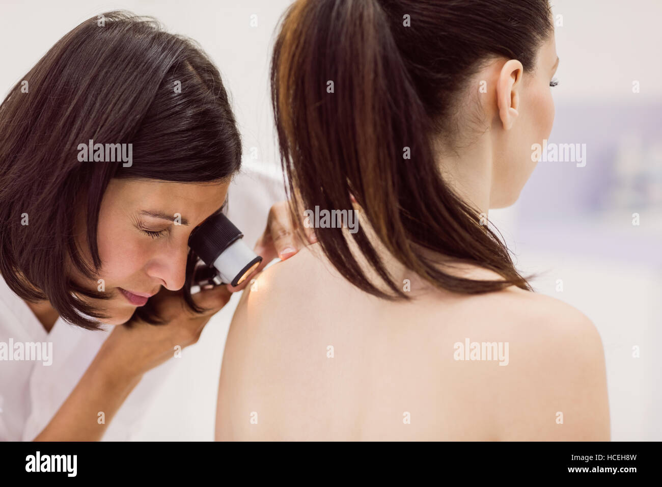 Dermatologist examining skin of patient with dermatoscope Stock Photo