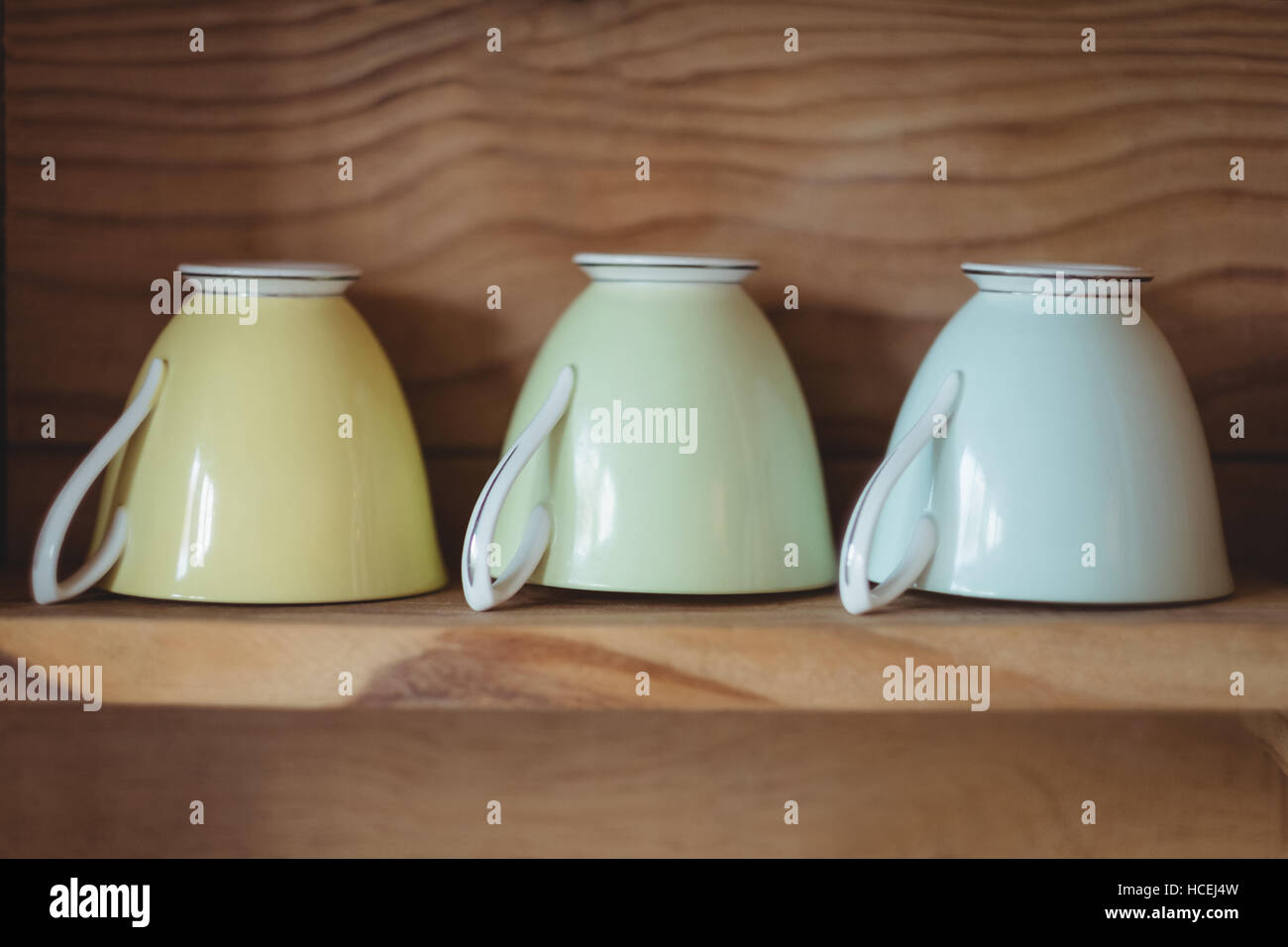 Teacups arranged in wooden shelf Stock Photo
