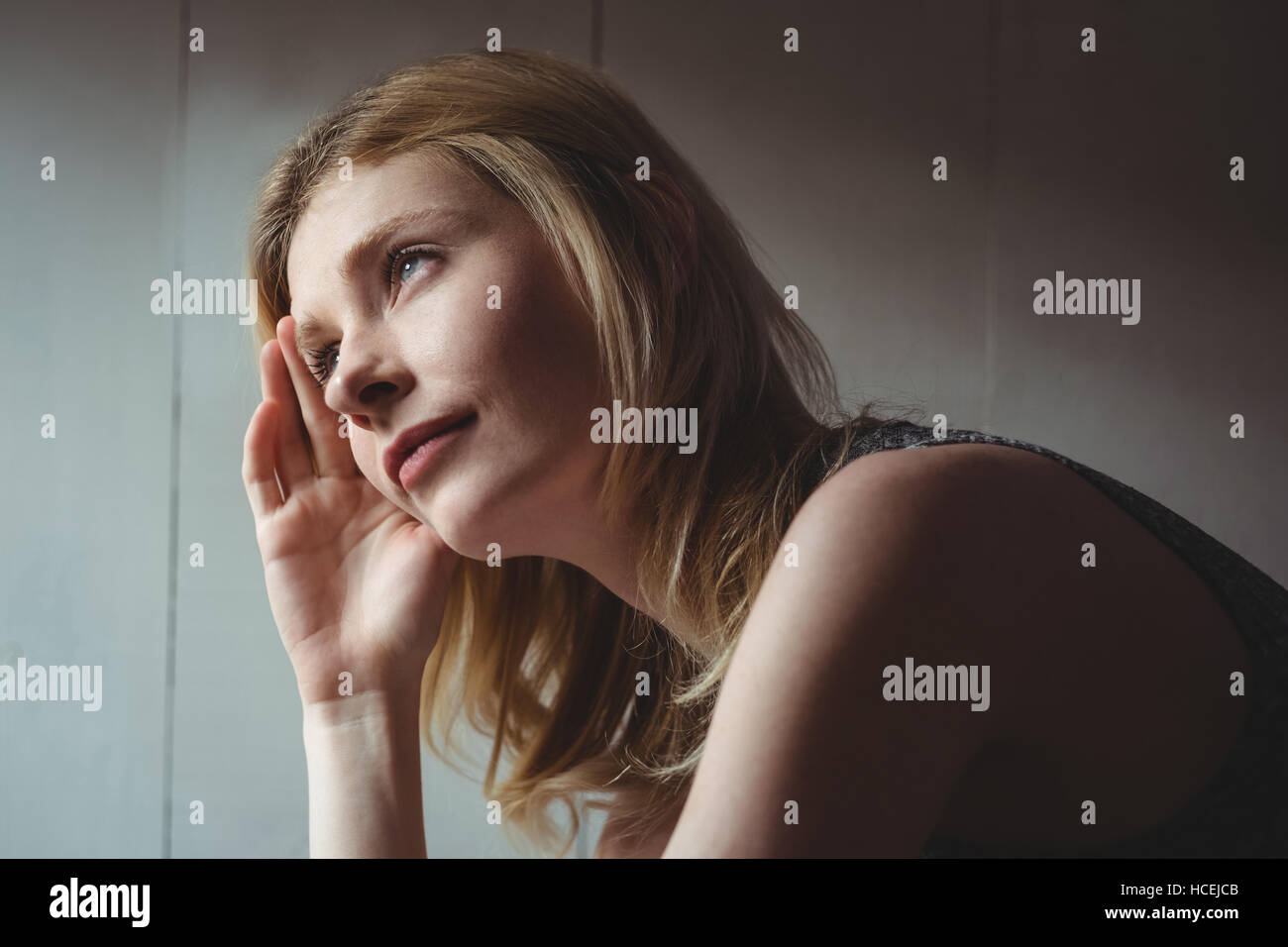 Thoughtful woman sitting with hand on forehead Stock Photo