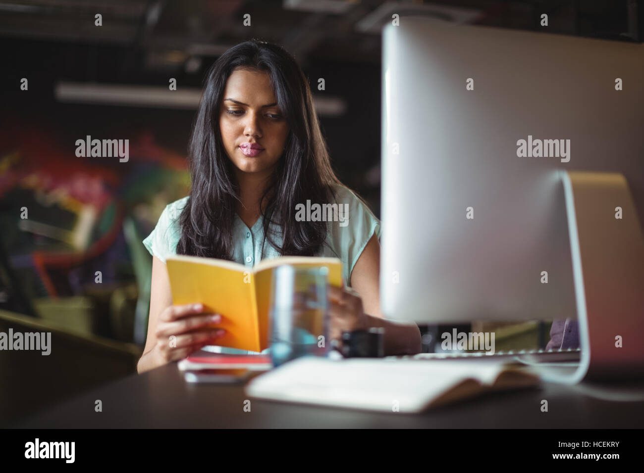 Businesswoman reading book at her desk Stock Photo