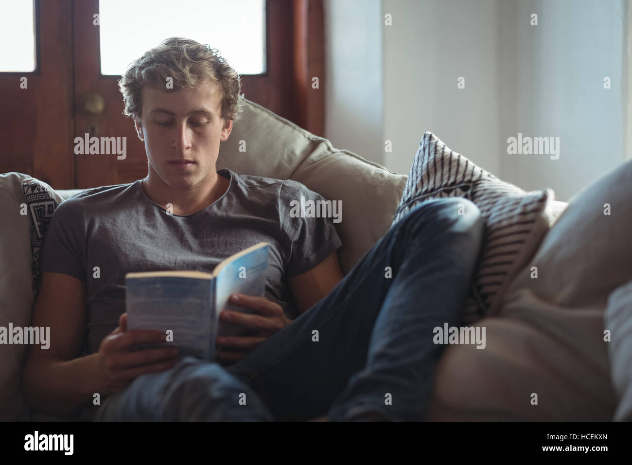 Man sitting on sofa reading a book Stock Photo Alamy