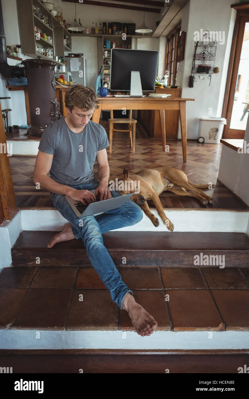 Man sitting on floor and using laptop, dog lying beside him Stock Photo