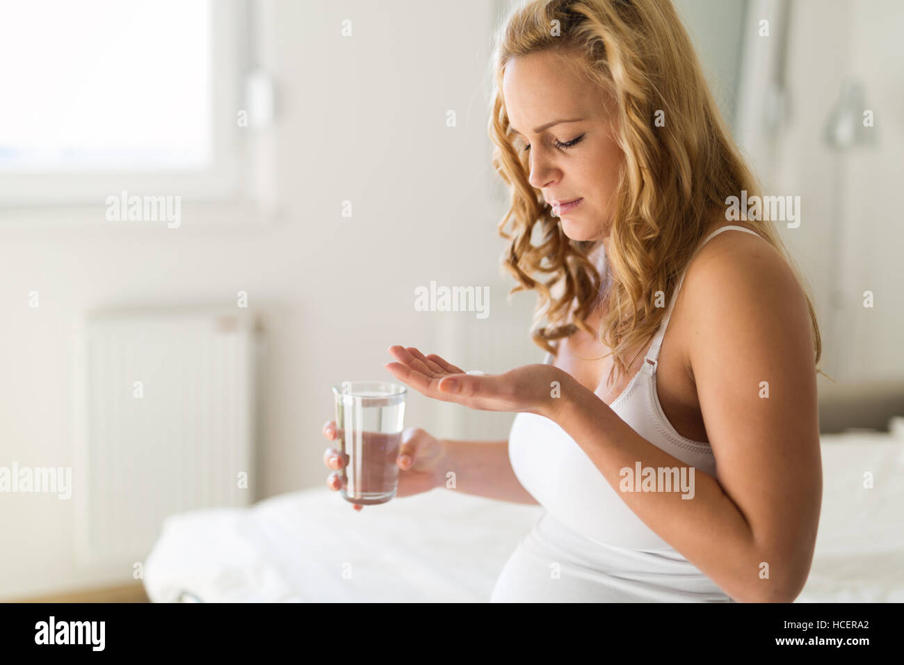 Pregnant woman taking pill against heartburn Stock Photo