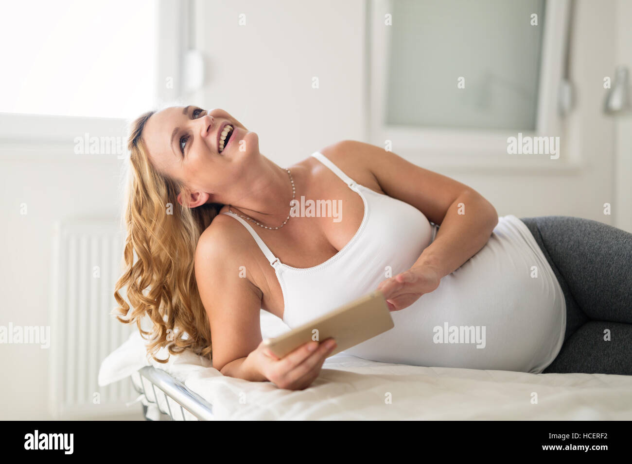 Pregnant woman relaxing and using tablet at home Stock Photo