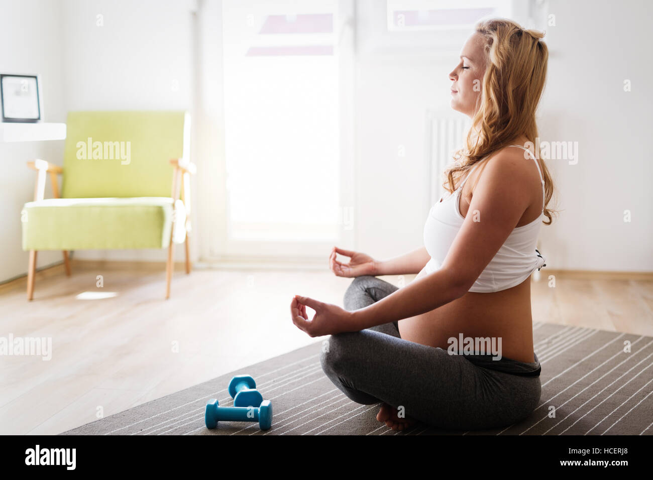 Pregnant woman in lotus posture practicing yoga Stock Photo