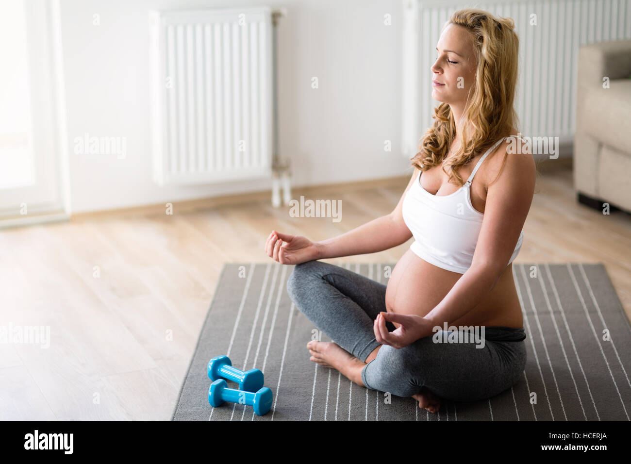 Pregnant woman in lotus posture practicing yoga Stock Photo