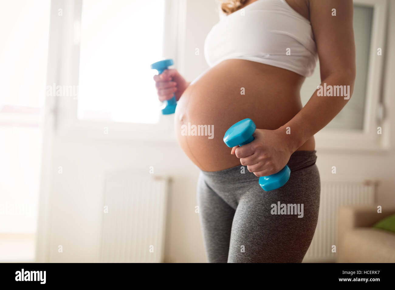 Pregnant woman training with dumbbells to stay active Stock Photo