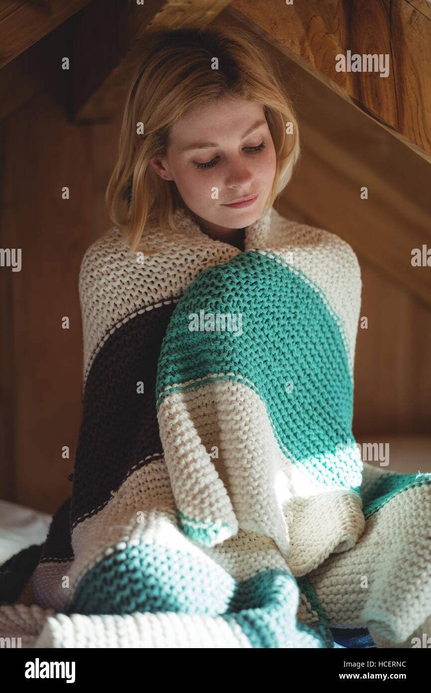 Beautiful woman wrapped in woolen blanket in bedroom Stock Photo
