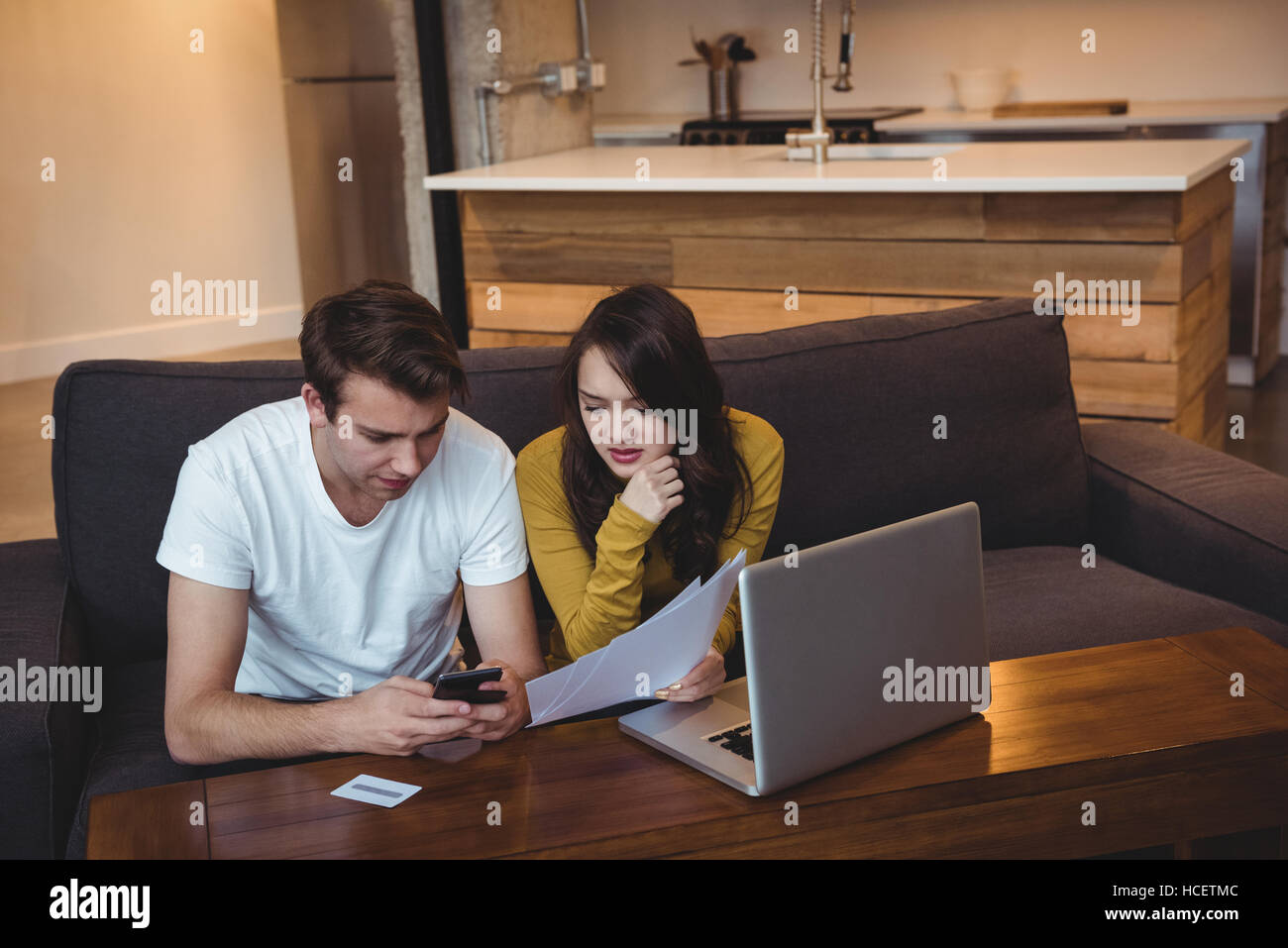 Couple sitting on sofa discussing with financial documents in living room Stock Photo