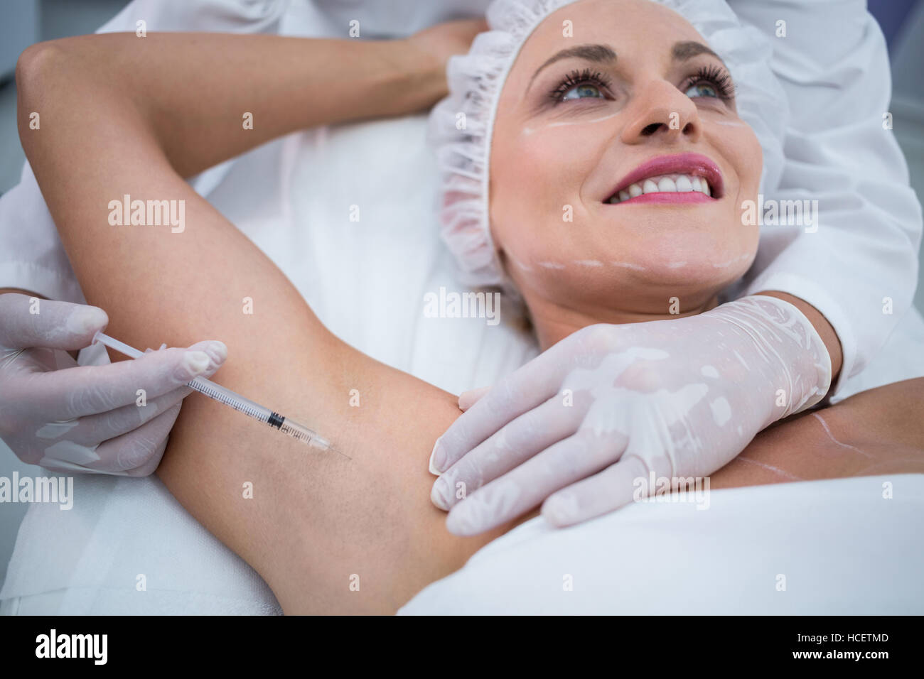 Doctor injecting woman on her arm pits Stock Photo