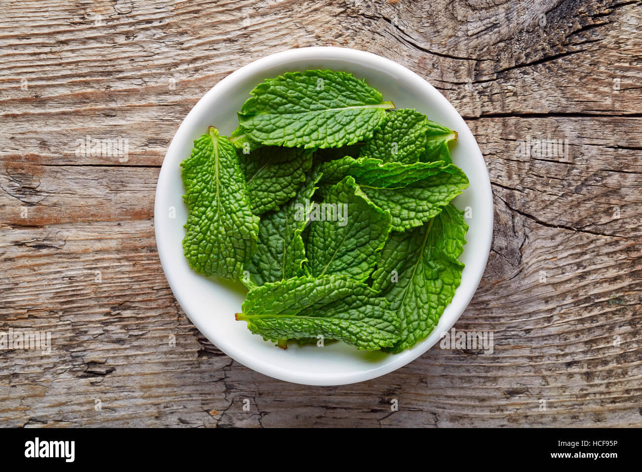 Bowl of mint leaves on wooden background, top view Stock Photo