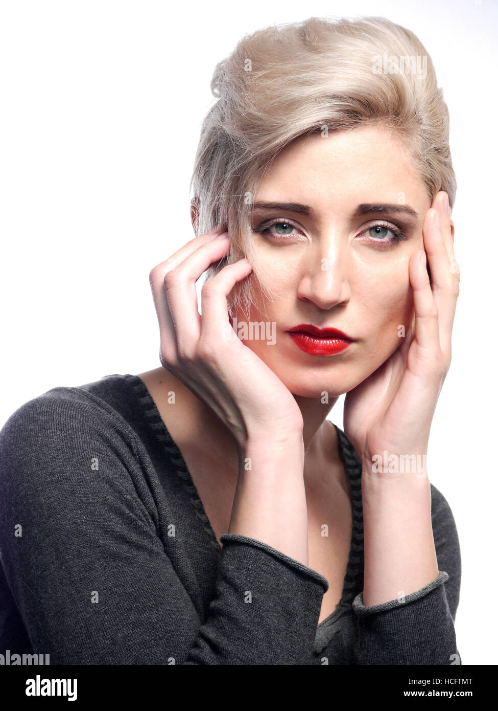 A studio image of a white woman with her hands up to her face on a white background. Stock Photo