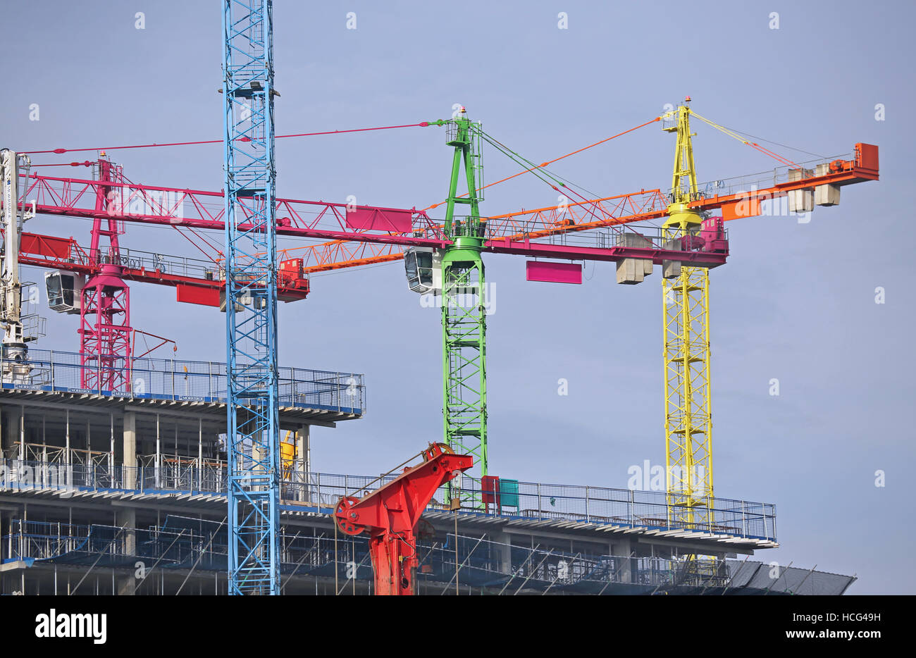Multi-coloured tower cranes on a large building project in North Greenwich, London, UK Stock Photo