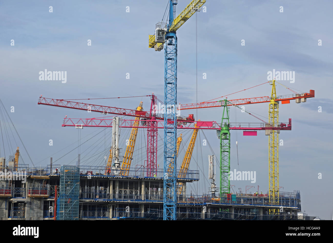 Multi-coloured tower cranes on a large building project in North Greenwich, London, UK Stock Photo