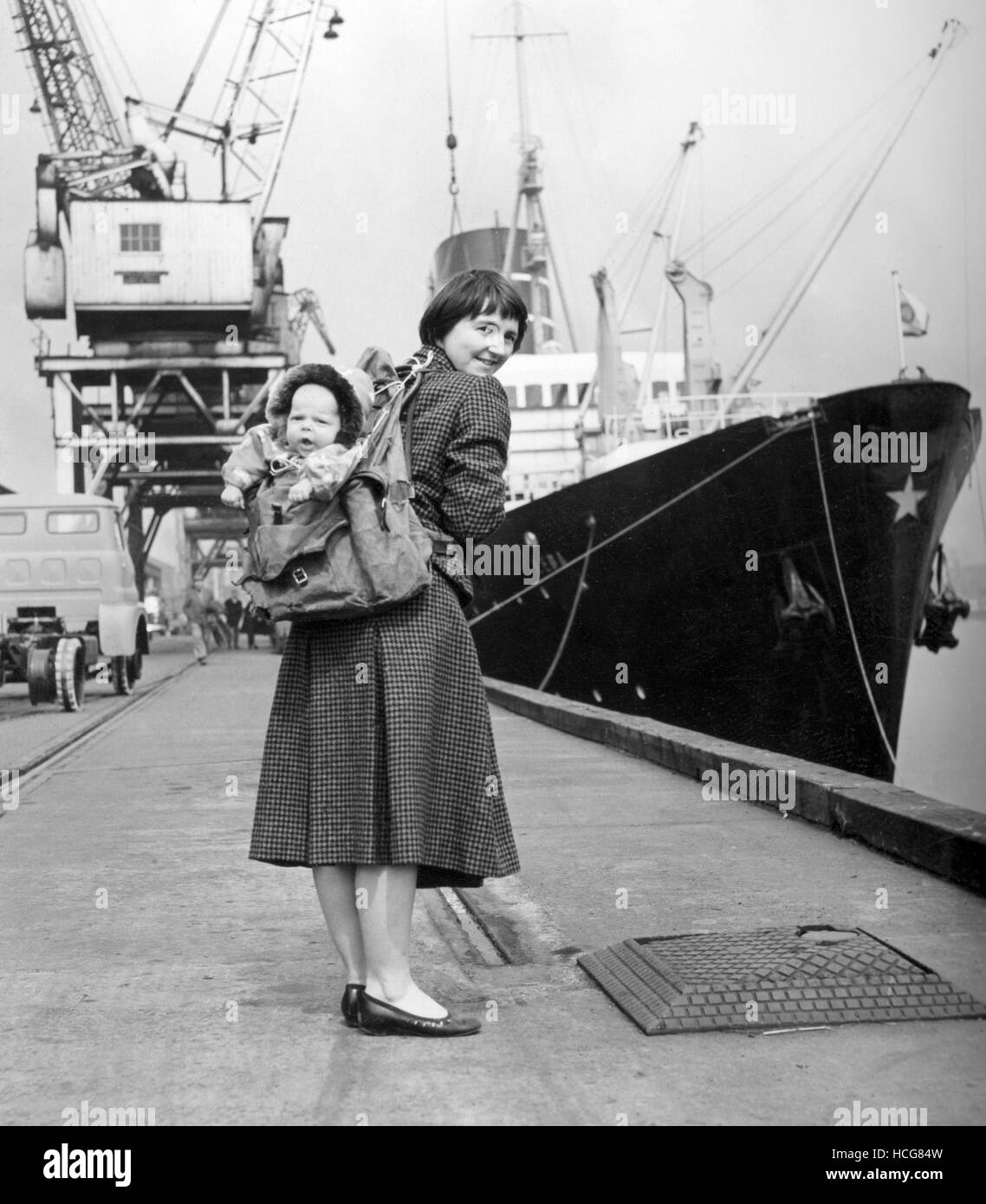 Wearing fur-lined clothes made from his Grandmother's sable evening cloak, four-month-old baby Robin Simpson is attached to his mother via rucksack, prior to departure in the Leda at Newcastle-upon-Tyne, on a journey that is to take them to Spitzbergen for a five-month visit. Robin's mother Myrtle, wife of Dr Hugh Simpson, is going to the Arctic, together with her husband, to take part in an expedition organised to carry out research into the effect of continuous daylight on human beings. Packed amongst the maps, ice picks, instruments and other exploration essentials, are the important Stock Photo