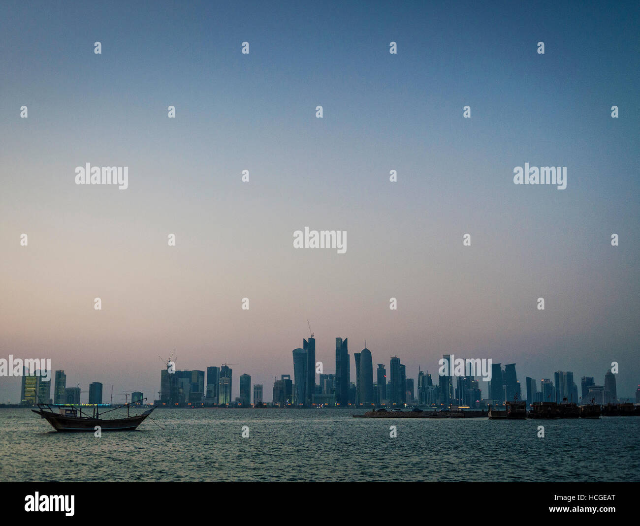 doha city skyscrapers urban skyline view and dhow boat in qatar at sunset Stock Photo