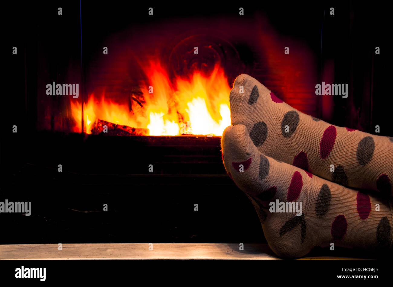 Feet in socks of all the family relaxing and warming by cozy fire Stock Photo