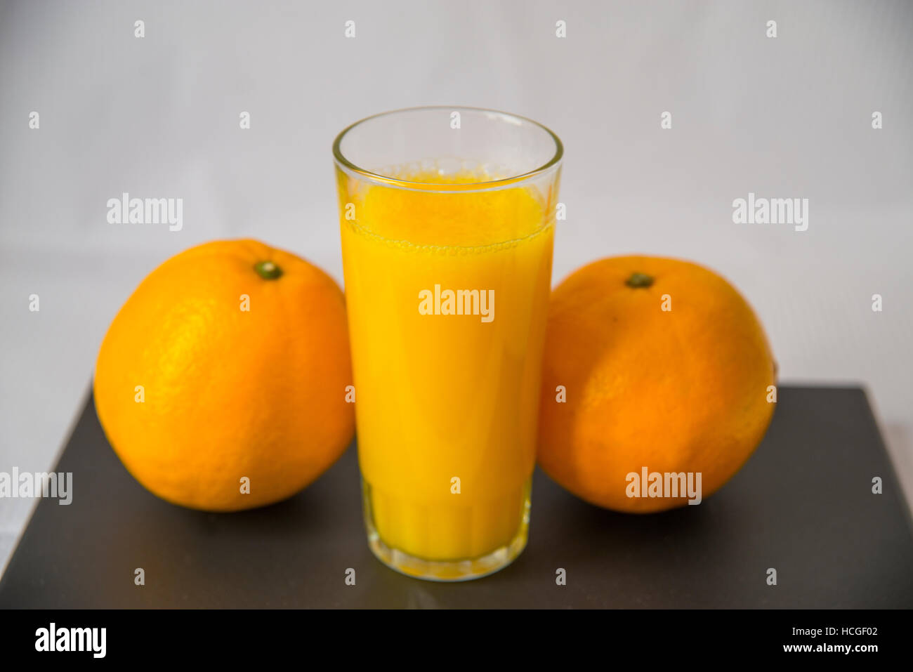 Glass of orange juice and two oranges. Still life. Stock Photo