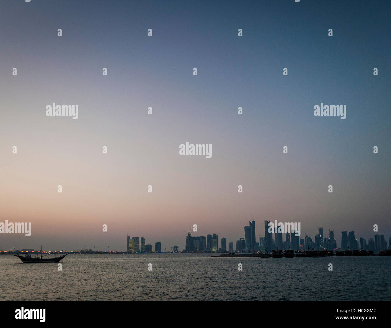 doha city skyscrapers urban skyline view and dhow boat in qatar at sunset Stock Photo