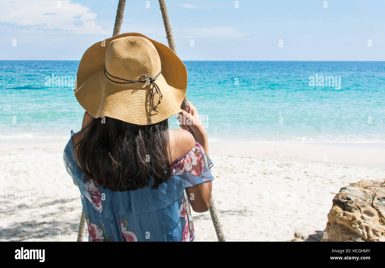 Girl sitting on a wooden swing on the beach. Summer holiday goals Stock Photo