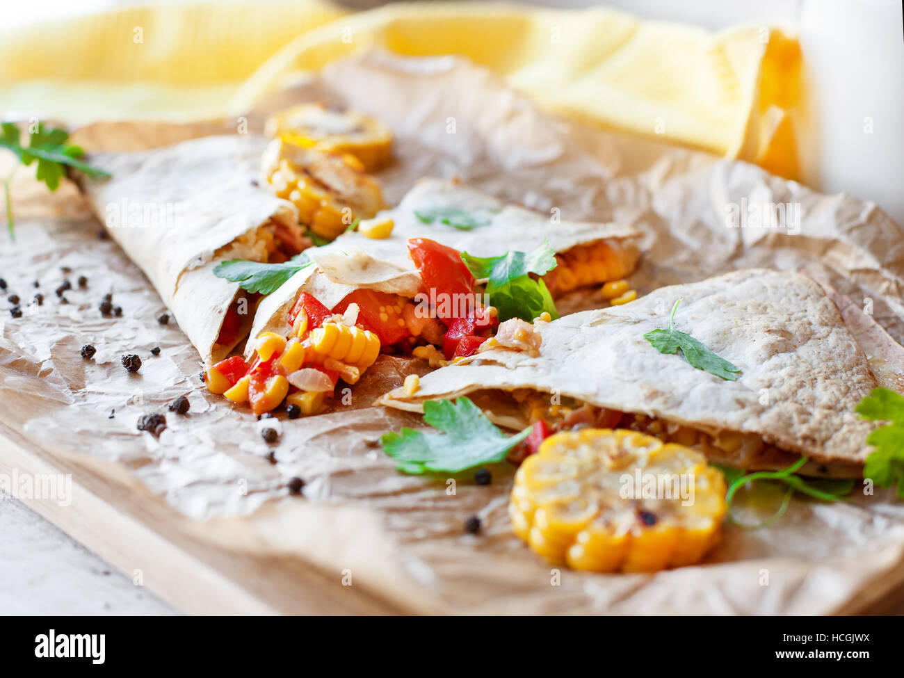 Mexican Quesadilla wrap with vegetables, corn, sweet pepper and sauces on the parchment and table. horizontal view. Stock Photo
