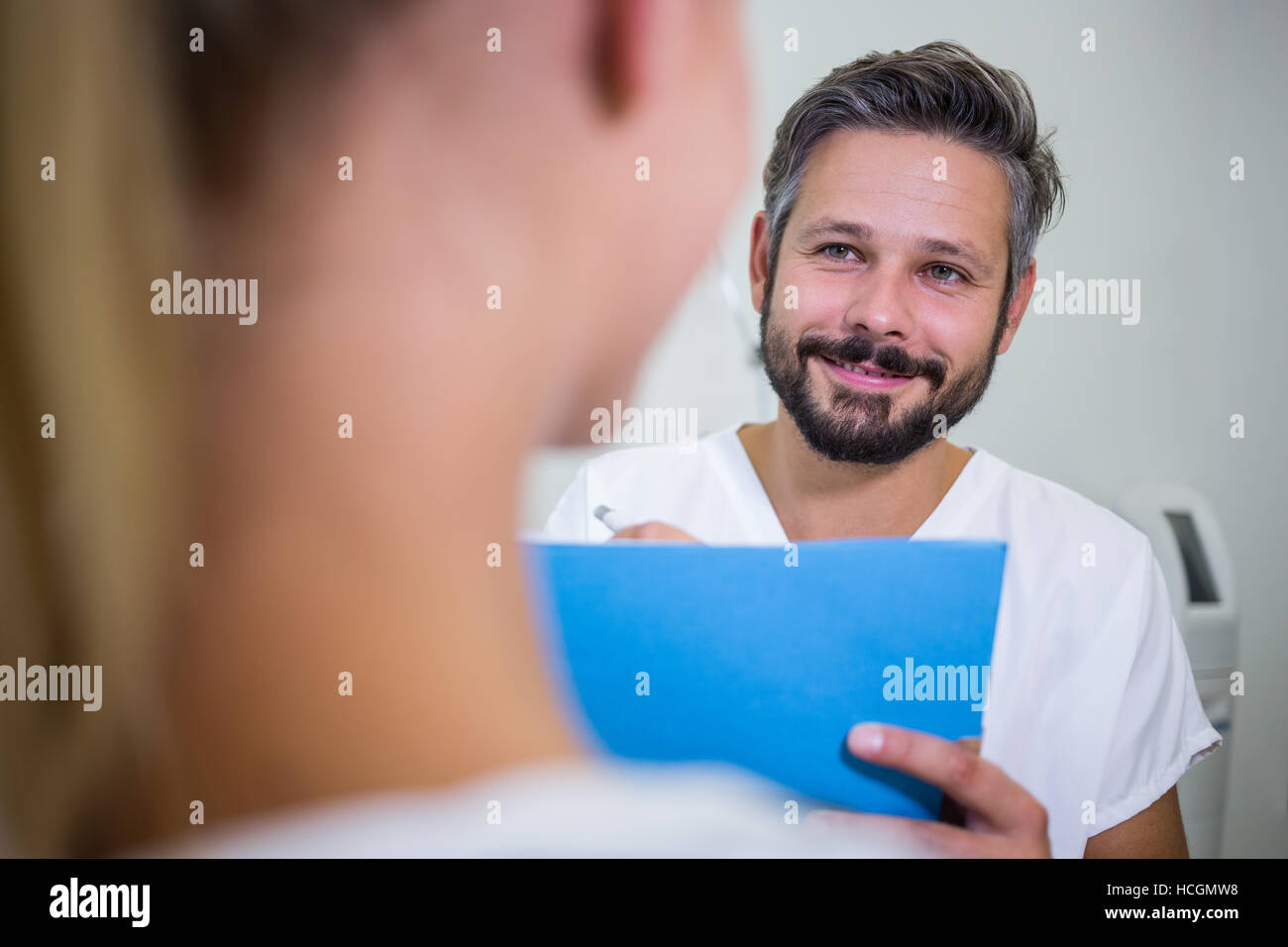 Doctor writing on reports while discussing with patient Stock Photo