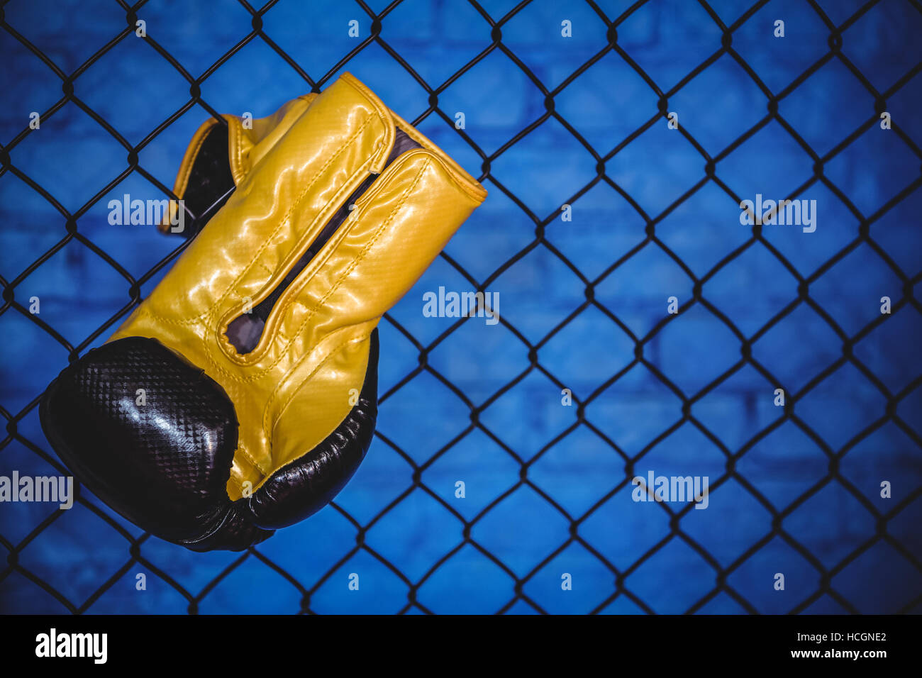 Boxing glove hanging on wire mesh fence Stock Photo