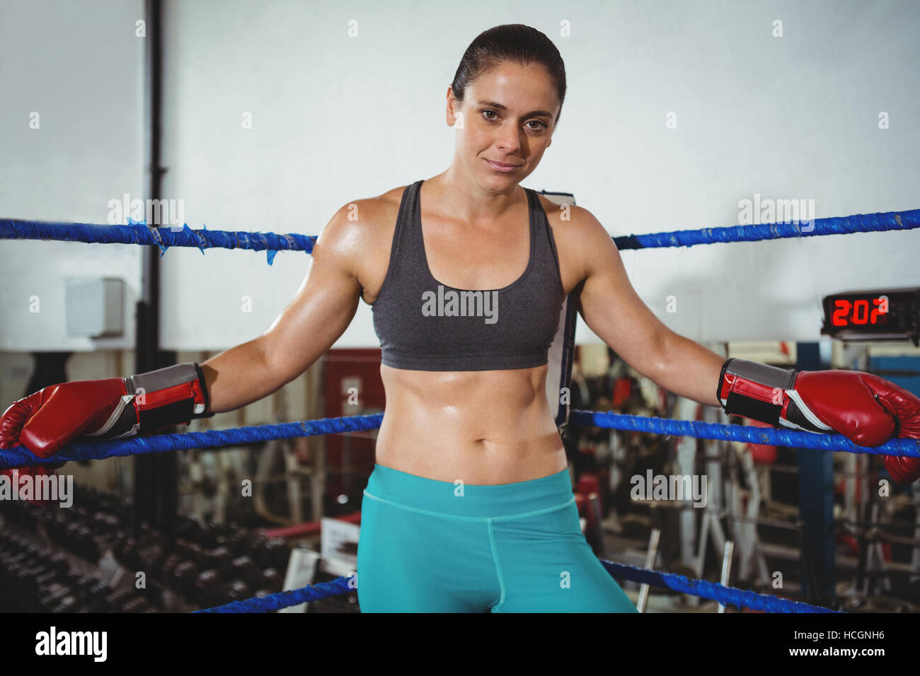 Confident female boxer leaning on boxing ring Stock Photo