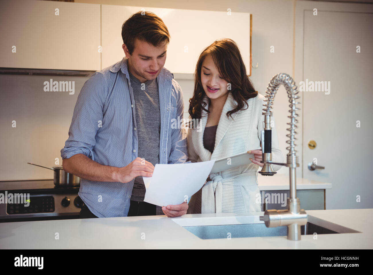 Couple discussing over digital tablet in kitchen Stock Photo