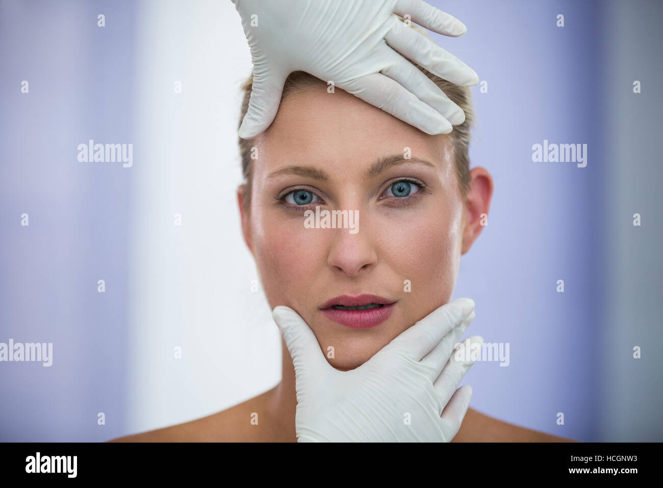 Doctor examining female patients face from cosmetic treatment Stock Photo