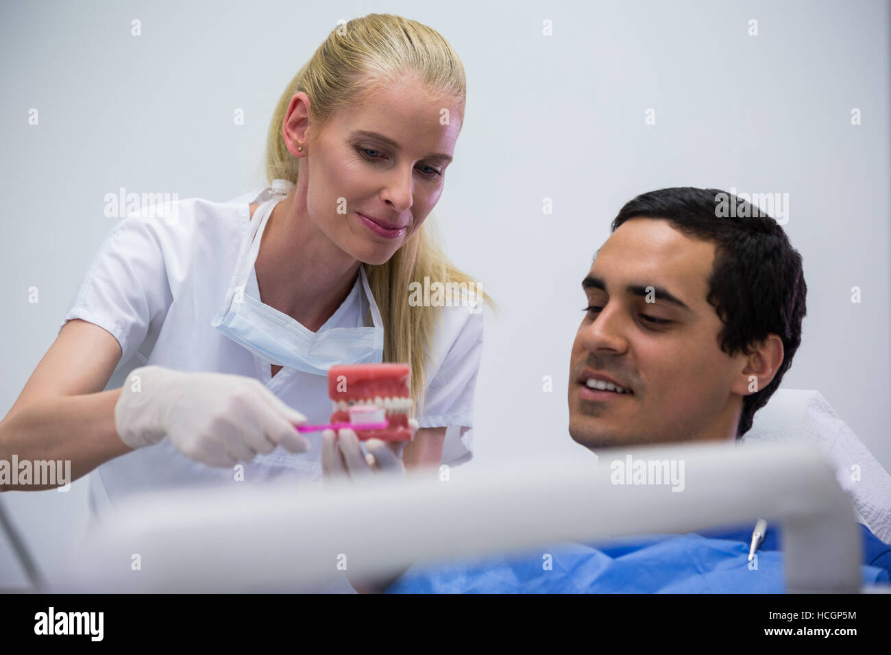 Dentist showing set of model teeth to the patient Stock Photo