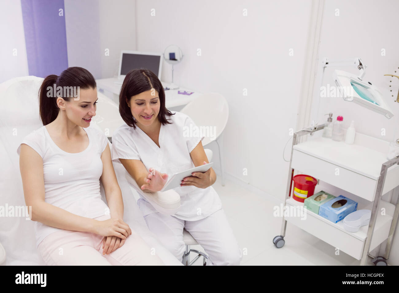 Dermatologist and female patient discussing on digital tablet Stock Photo