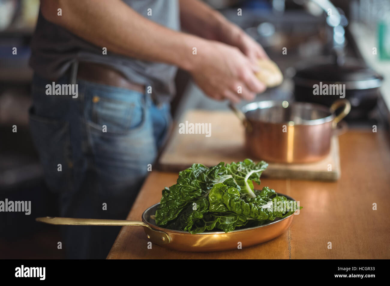 Lettuce on pan and man preparing food in kitchen Stock Photo