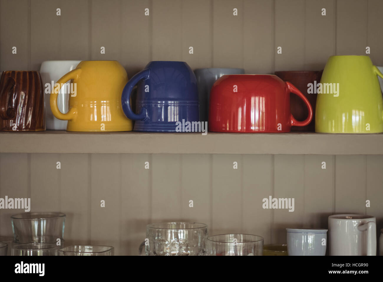 Colourful cups on kitchen shelf Stock Photo