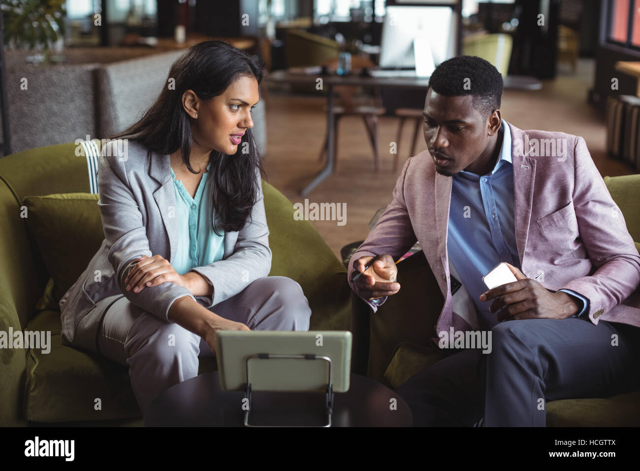 Businessman and a colleague discussing over digital tablet Stock Photo