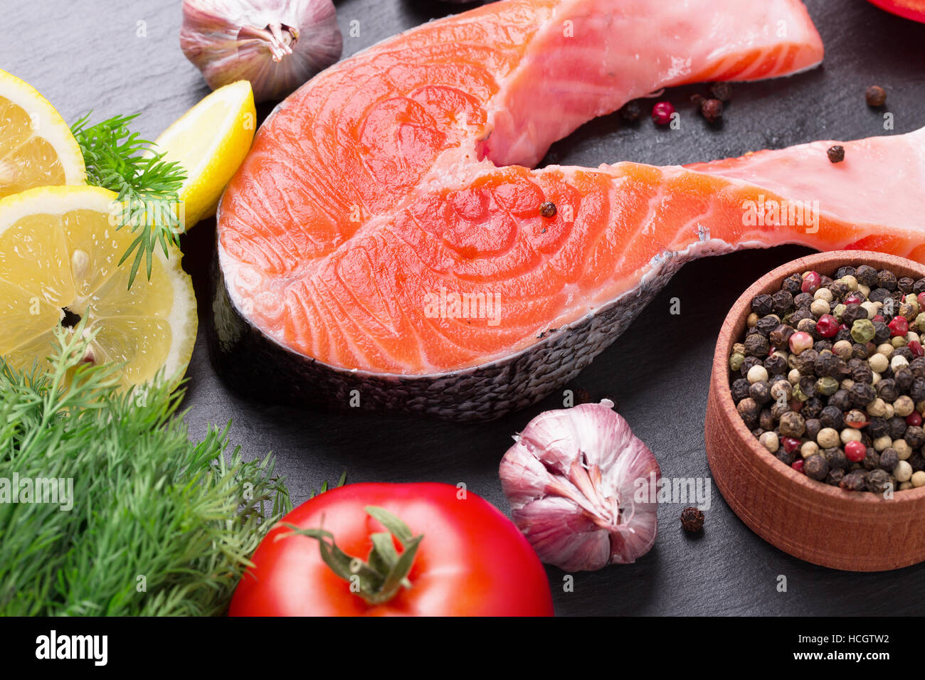 red fish steak with vegetables and spices on a slate table. Stock Photo