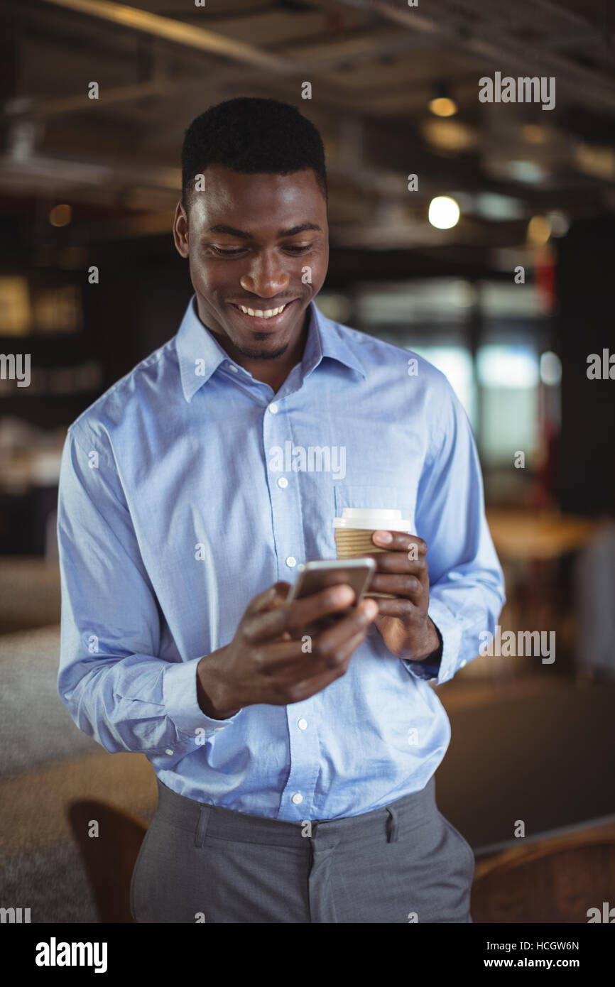 Businessman holding disposable coffee cup and using mobile phone Stock Photo