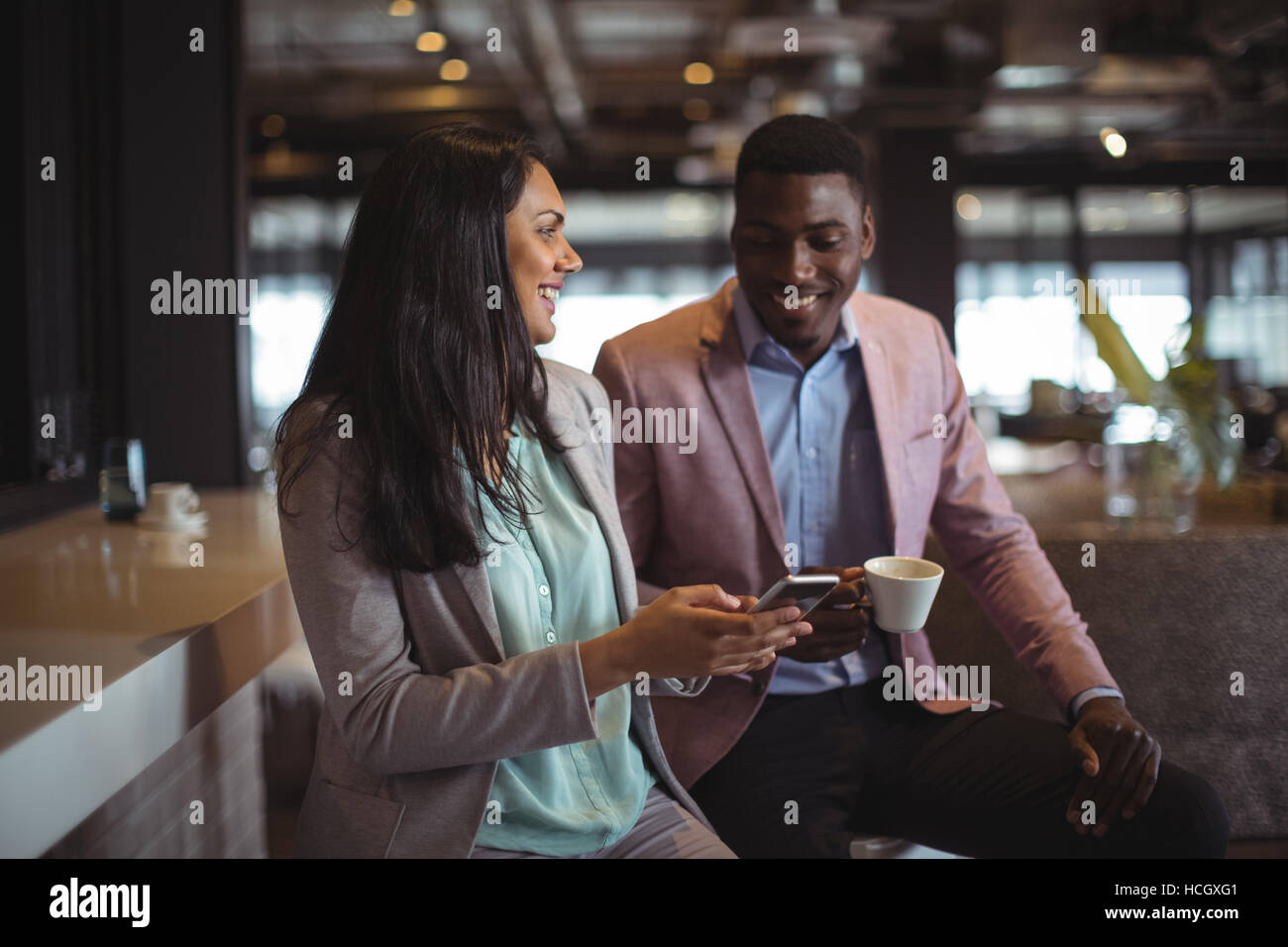 Businessman and a colleague discussing over mobile phone Stock Photo