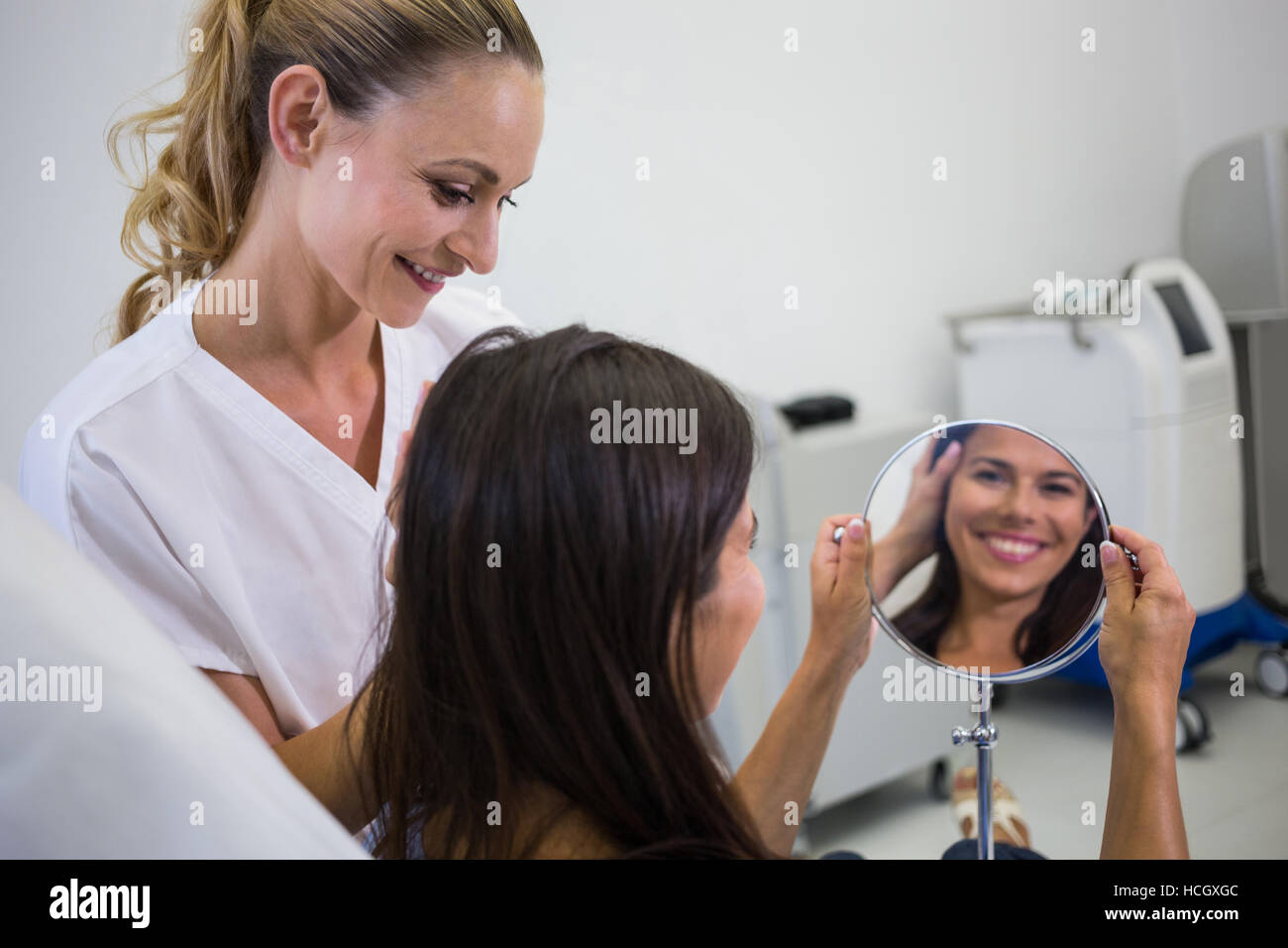 Woman checking her skin in the mirror after receiving cosmetic treatment Stock Photo